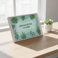 Tablet mockup displaying Breathe Better at Home eBook cover with plant imagery on a bright desk