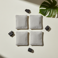 Overhead flat-lay of four linen bamboo charcoal bags with charcoal pieces and a green leaf